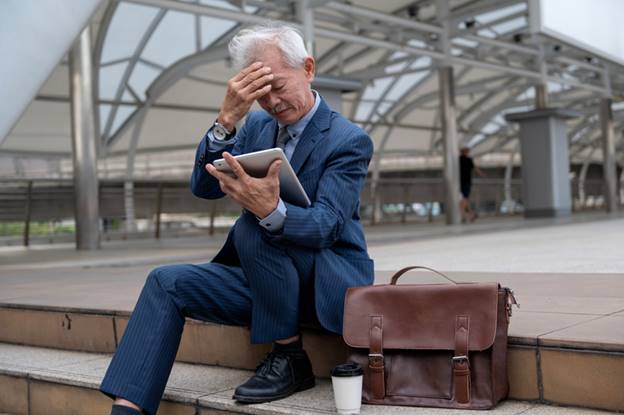 Older man sitting on steps in front of office - Age Discrimination